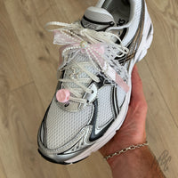 White satin shoe laces styled with pink lace bow, pearl bow charm, flower charm and lace accessories on ASICS trainers.