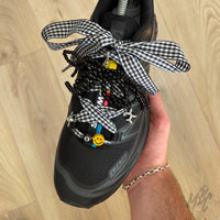 Black gingham ribbon shoe laces with black beaded bow, balloon dog charms, smiley bead and lace accessories on Salomon trainers.