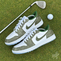 Pair of Emerald Reserve Jordan 1 Low Golf custom golf trainers photographed on a golf green with golf club and ball