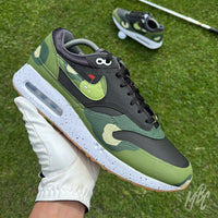 Nike Air Max 1 Fairway Camo custom golf sneaker in hand on course with green camouflage design