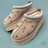 Pair of beige UGG Tazz II slippers with pyrography burnt onto the suede