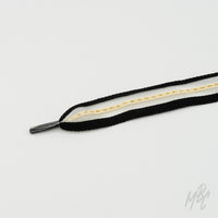 Black and white sneaker laces featuring gold stripe detailing and layered woven construction for custom trainers