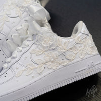 Detail shot of lace floral appliqué stitched onto white Air Force 1 with hand-placed pearl accents