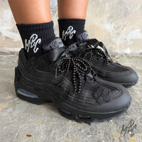 Midnight Veil custom Nike Air Max 95 trainers worn on foot, featuring black floral appliqués, satin ribbon laces, black beaded laces and an all-black hand-customised finish.