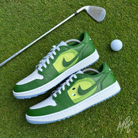 Pair of Pin Position custom Jordan 1 Low Golf shoes with hand-painted golf fairway artwork displayed on a putting green beside a golf club and ball.