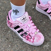 Pink Overgrown custom Adidas Superstar worn on foot featuring hand-painted floral artwork, textured pink paint and black Adidas stripes.