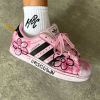 Close-up of the Pink Overgrown custom Adidas Superstar on foot, showcasing hand-painted pink flowers, textured brushstroke effects, black Adidas stripes and custom "Overgrown" midsole artwork.