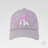 Gradient Swipe custom New Era NY cap featuring a hand-painted pink gradient logo, abstract purple paint swipes and white paint splatter detailing.