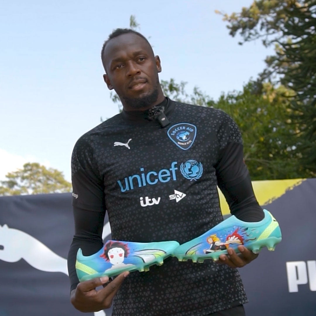 Mo Farah holding his custom Puma football boots he wore for the Soccer Aid game