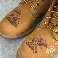 Close-up of cherub tattoo artwork engraved into tan suede Timberland boots using hand engraving techniques