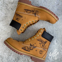Tattoo-style cherub illustrations engraved into tan Timberland 6 Inch boots using pyrography for a permanent suede finish