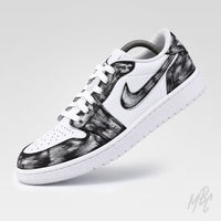 A low-top Nike sneaker featuring a white leather base with a black and gray brushstroke pattern on the overlays, white laces, and a white midsole.