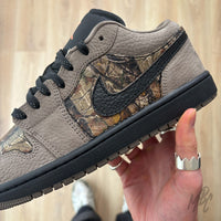 Woodland Camo Jordan 1 Low custom in hand showing camo side panel and black swoosh detail