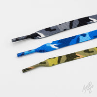 Three flat camouflage shoelaces in grey, blue, and green with matching patterned aglets, arranged on a white background.