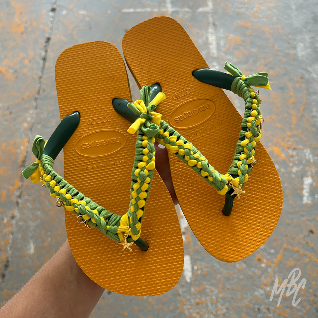 Sunwoven Carnival custom Havaianas featuring handcrafted yellow and green braided straps with gold starfish and turtle charms.
