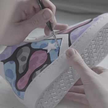 hand painting a bubble design on a pair of converse shoes