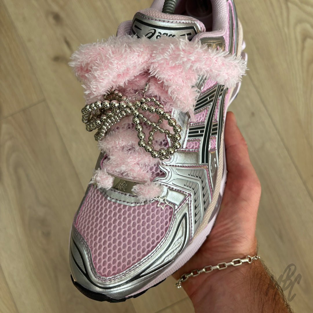 Pink fluffy shoe laces with silver beaded bow charm, star charm and lace accessories styled on pink ASICS trainers.