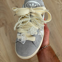 Cream rope shoe laces styled with pearl bow charm, embroidered flower patches and silver lace charms on Adidas Campus trainers.