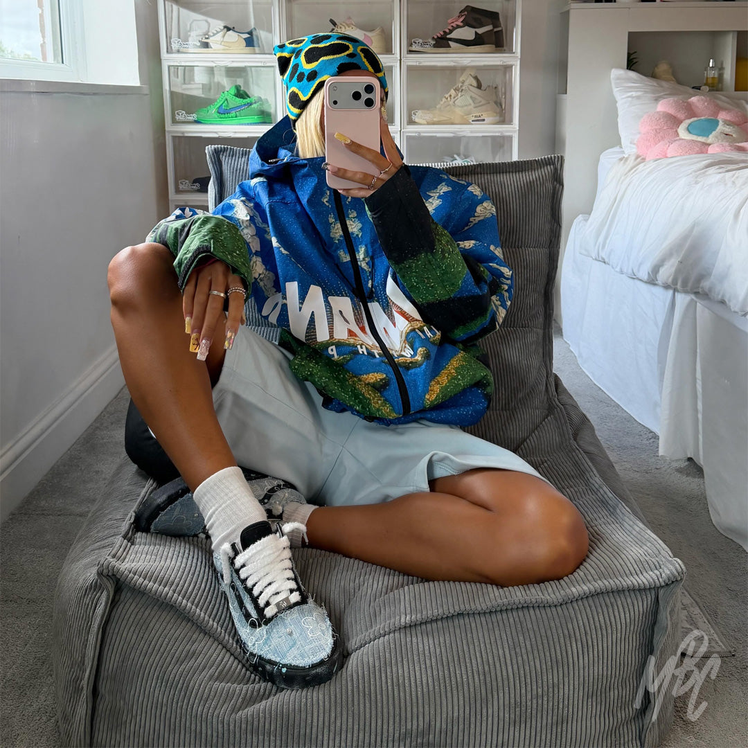 Model wearing custom Denim Bloom Vans Old Skool trainers with fluffy white laces, featuring distressed denim, floral artwork and hand-painted details.