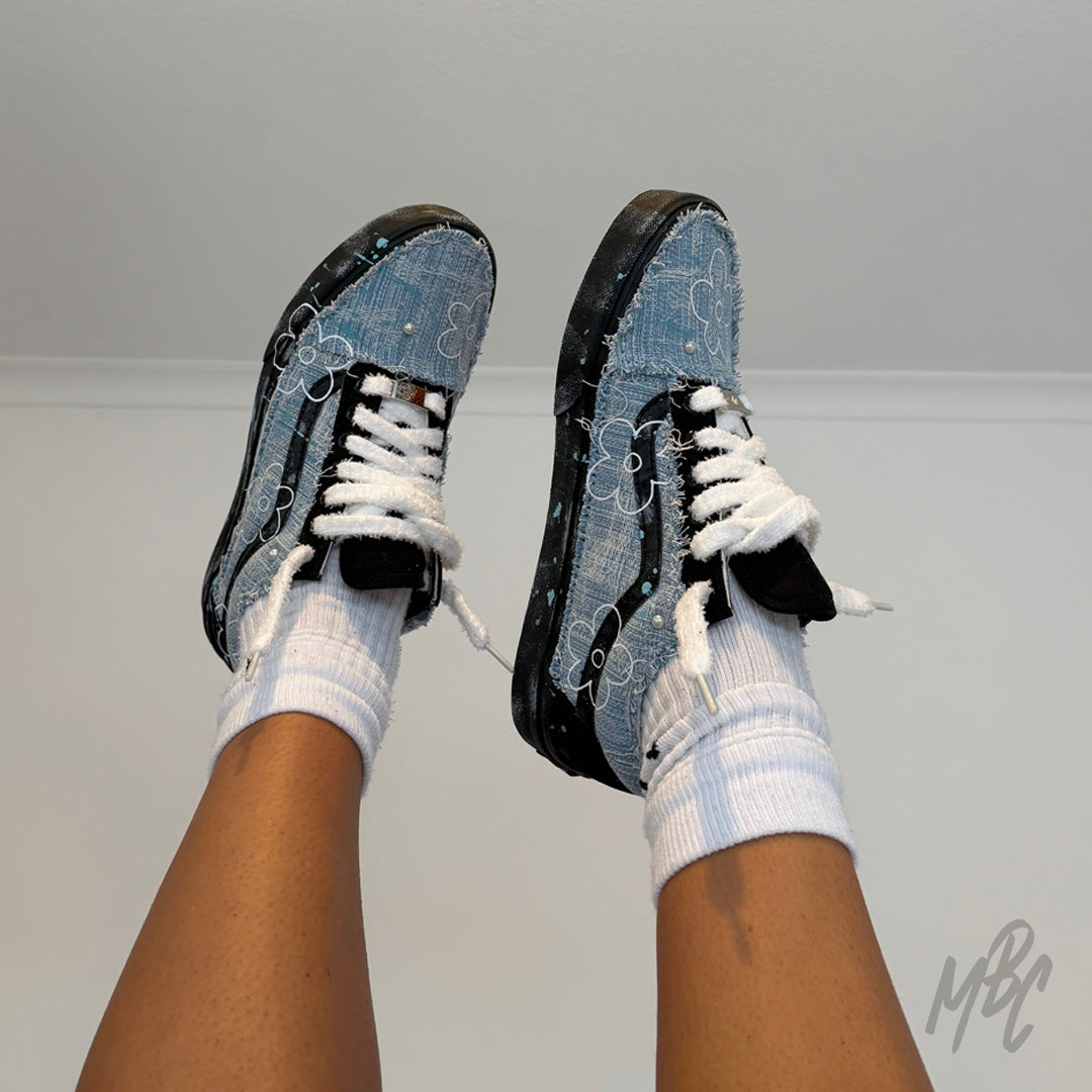 On-foot view of custom Denim Bloom Vans Old Skool sneakers with fluffy white laces, distressed denim panels and floral hand-painted design.