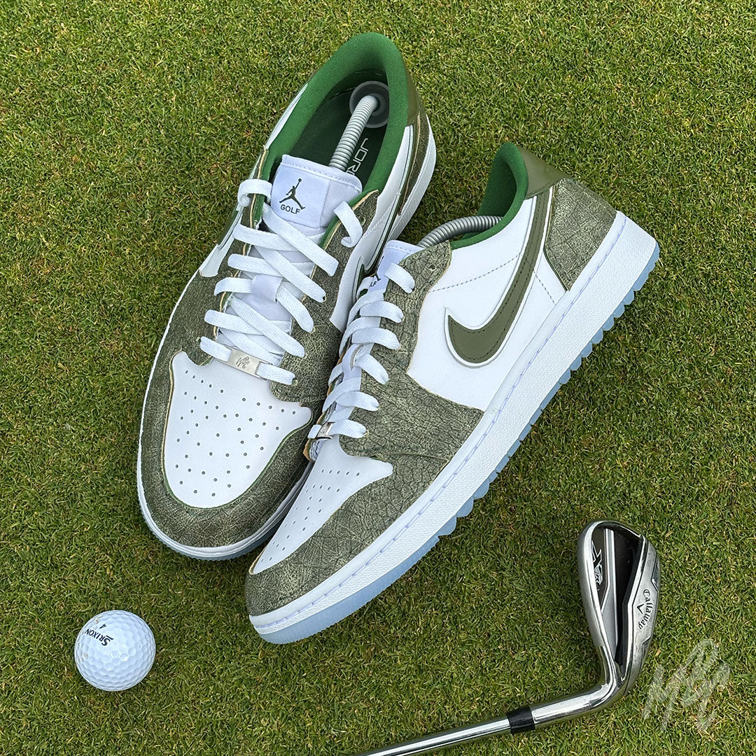 Top-down view of Emerald Reserve Jordan 1 Low Golf custom golf shoes on a putting green with golf ball and iron club