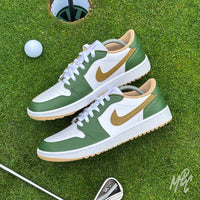 Pair of Fairway Gold custom Jordan 1 Low Golf shoes with hand-painted green and gold leather panels displayed on a putting green with a golf club and ball.