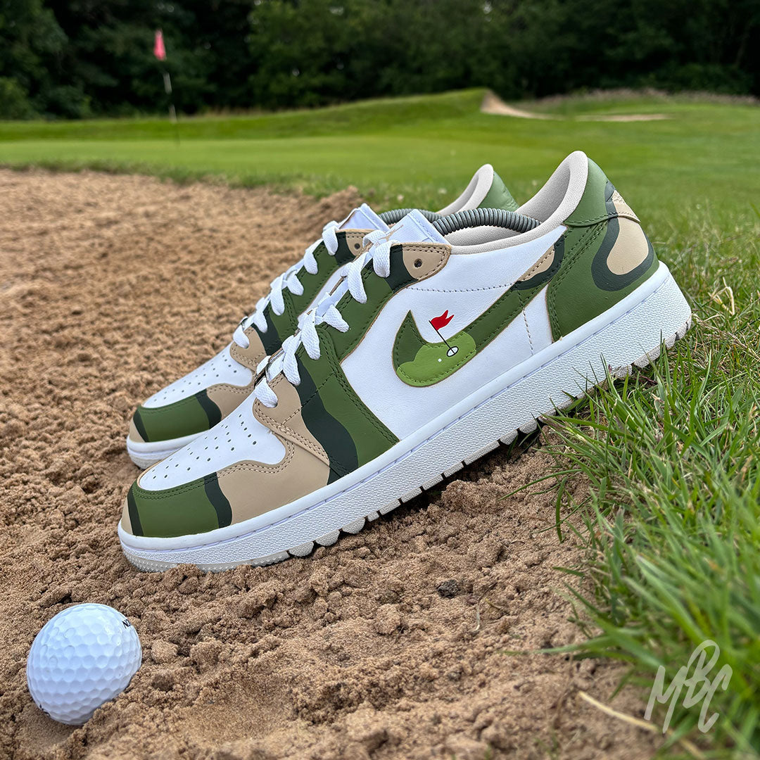 Fairway Camo Jordan 1 Low Golf custom golf shoes positioned in a bunker beside a golf ball on the course