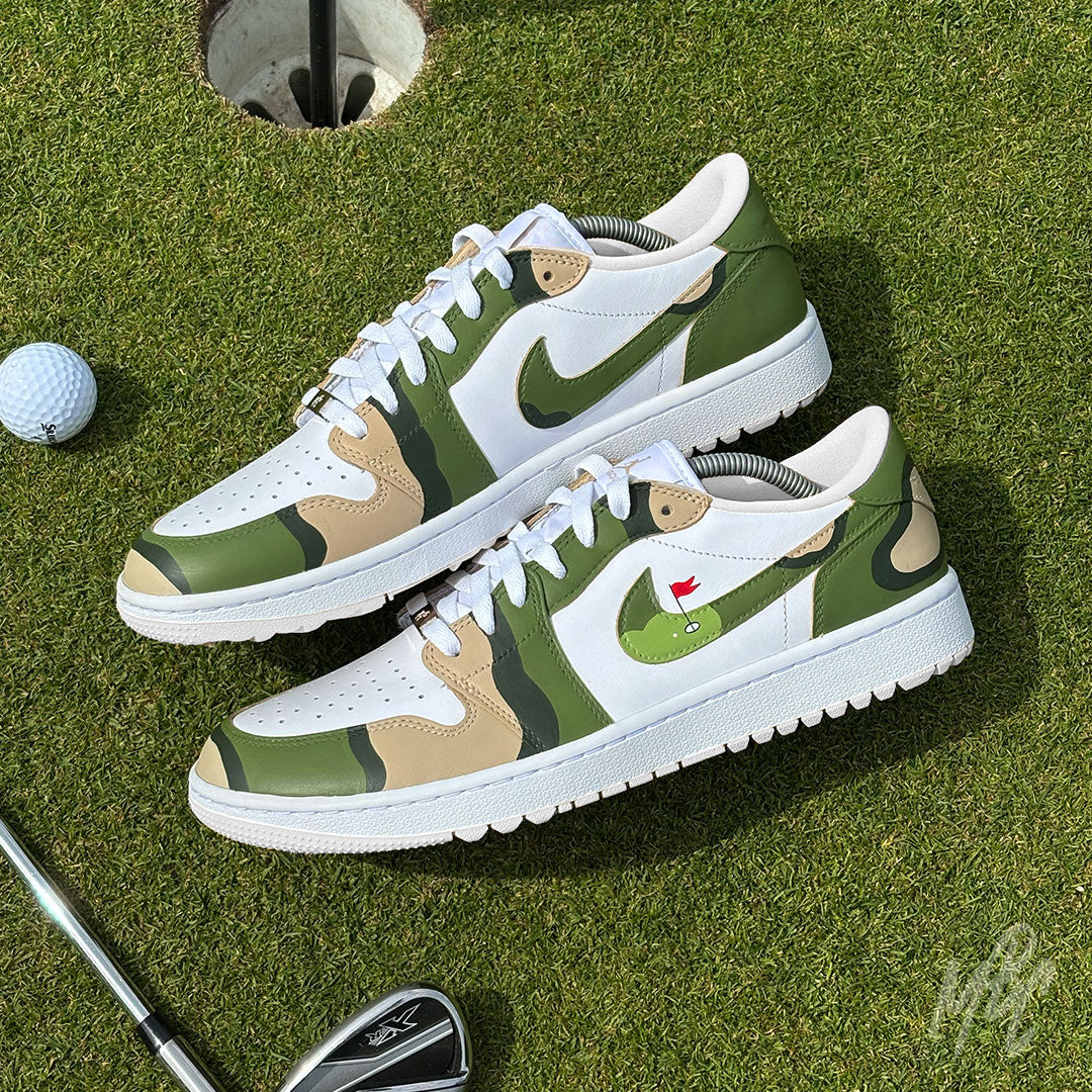 Custom Fairway Camo Jordan 1 Low Golf trainers on the putting green beside a golf hole and golf club