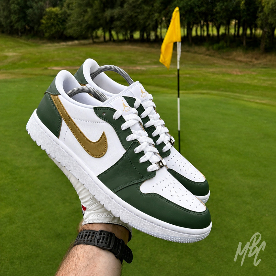 Pair of Fairway Gold custom Jordan 1 Low Golf shoes with hand-painted green and gold colour blocking, held above a golf green beside the pin.