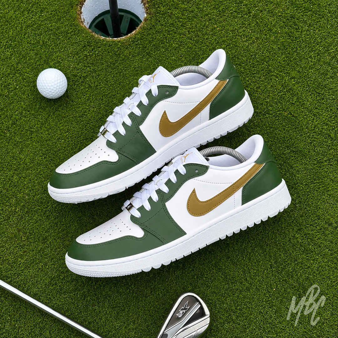 Pair of Fairway Gold custom Jordan 1 Low Golf shoes with hand-painted green and gold leather panels displayed on a putting green with a golf club and ball.