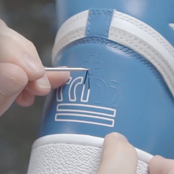 hand painting chelsea football club on a pair of custom Jordan trainers
