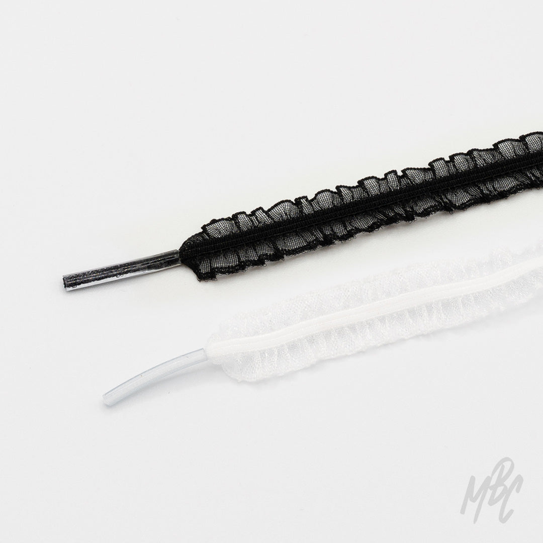 Black and white mesh shoelaces with ruffled edges and clear plastic aglets arranged on a white background.