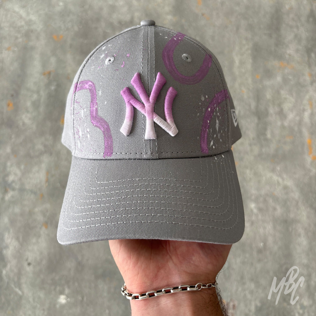 Gradient Swipe custom New Era New York Yankees cap featuring a grey crown, pink ombré embroidered NY logo, hand-painted purple gradient swipe graphics and white paint splatter detailing.