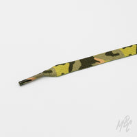 Close-up of a flat green camouflage shoelace with a matching patterned aglet on a white background.