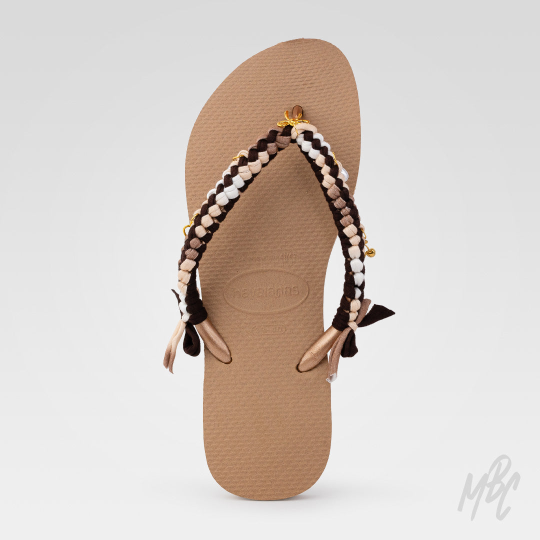 Top view of a brown Havaianas flip-flop customised with dark brown, beige, white and taupe braided straps and gold charms.