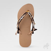 Top view of a brown Havaianas flip-flop customised with dark brown, beige, white and taupe braided straps and gold charms.