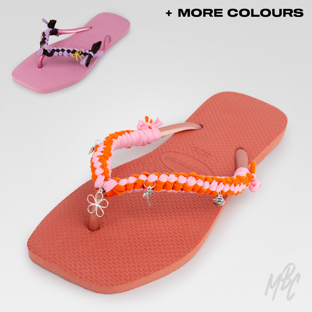 Angled view of a peach Havaianas flip-flop featuring pink and orange braided straps with silver flower, palm tree and shell charms.