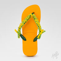 Top view of Sunwoven Carnival custom Havaianas showcasing handcrafted braided straps, gold charms and vibrant yellow flip flops.