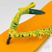 Close-up of Sunwoven Carnival custom Havaianas featuring handcrafted yellow and green braided straps with gold starfish and turtle charms.