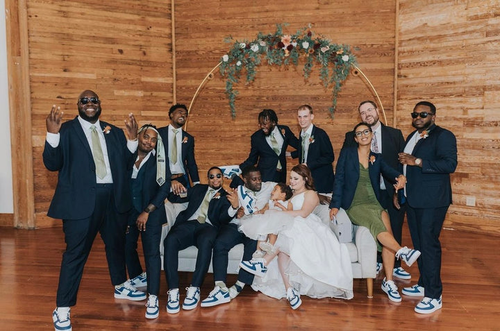 bride and groom with their wedding party wearing matching custom air force 1 trainers with a blue and green colourway, date and illustration of their venue