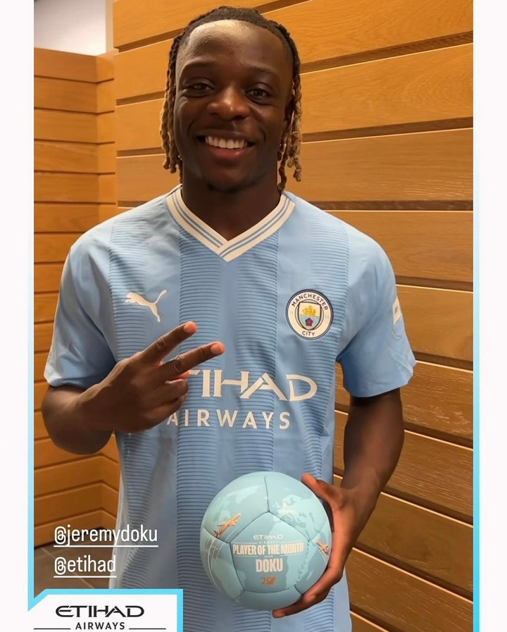 Doku holding his Manchester City Player of the Month custom football