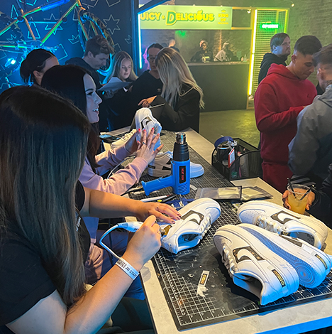 MattB Customs artists hand painting and ironing on vinyls on Air Force 1s at a JD Pop Up event