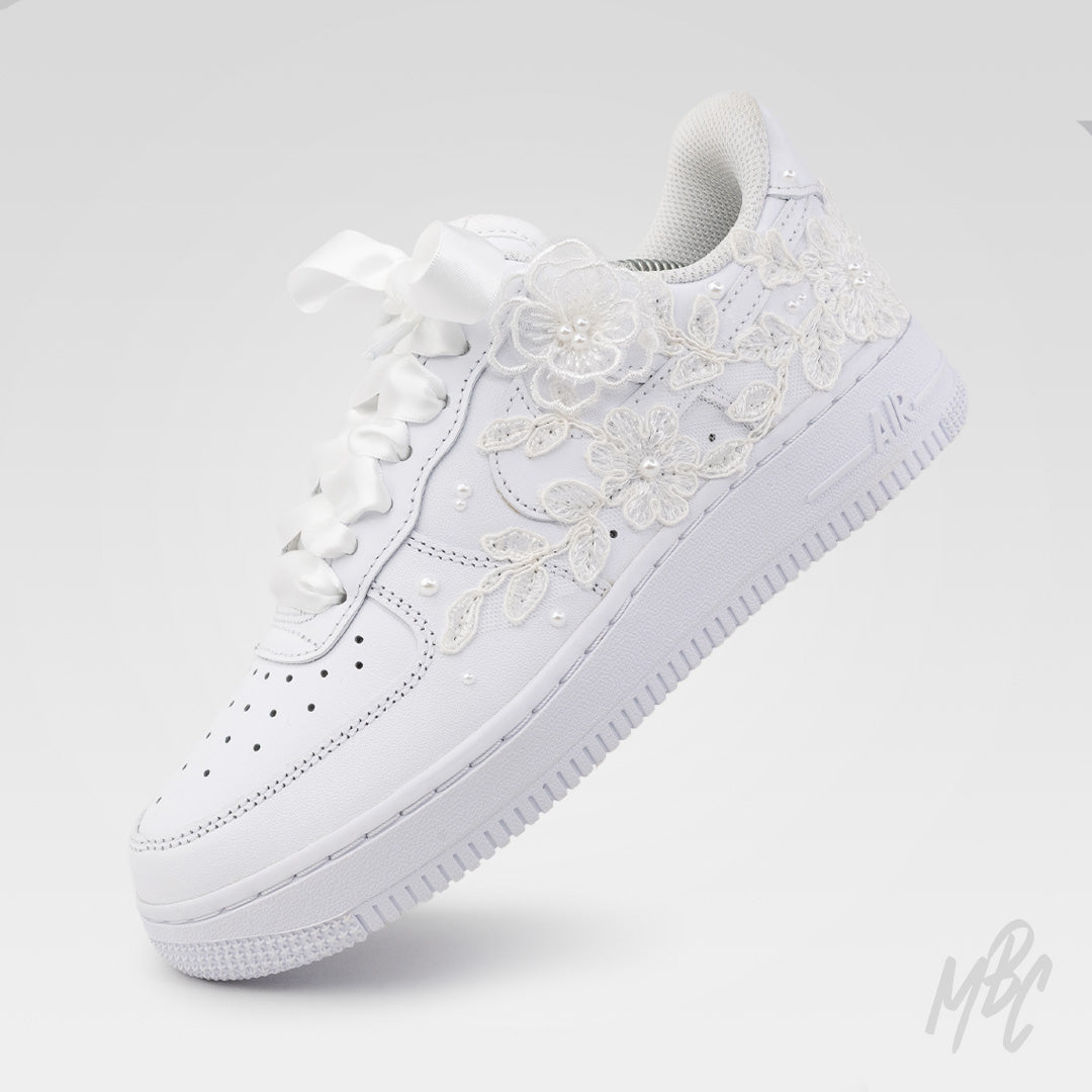 Angled view of white Air Force 1 custom with lace detailing, satin ribbon laces and white sole