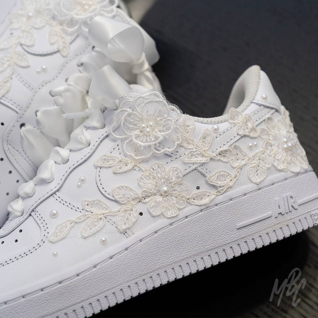 Detail shot of lace floral appliqué stitched onto white Air Force 1 with hand-placed pearl accents