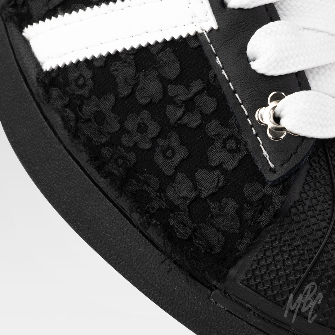 close up of black and white Adidas Superstar custom sneakers with a textured floral design 
