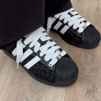 Black and white Adidas Superstar custom sneakers with a textured floral design on foot 