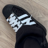 Black and white Adidas Superstar custom sneakers with a textured floral design on foot 