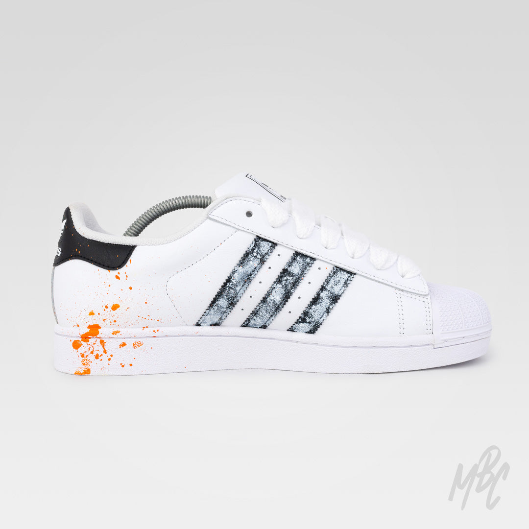 Inside view of Modern Relic custom Adidas Superstar with textured black painted stripes, orange paint splatters and hand-painted detailing.