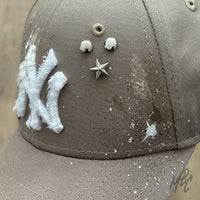 Close up of custom New Era NY cap with distressed logo, metal studs and paint splatter detailing