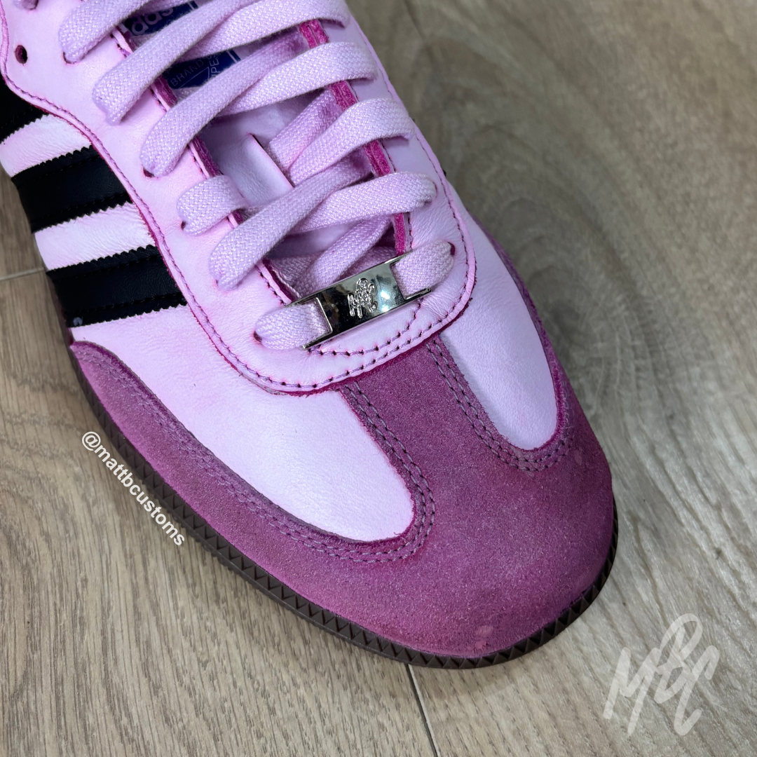 Pink and purple sneaker with a visible brand logo on a wooden floor.